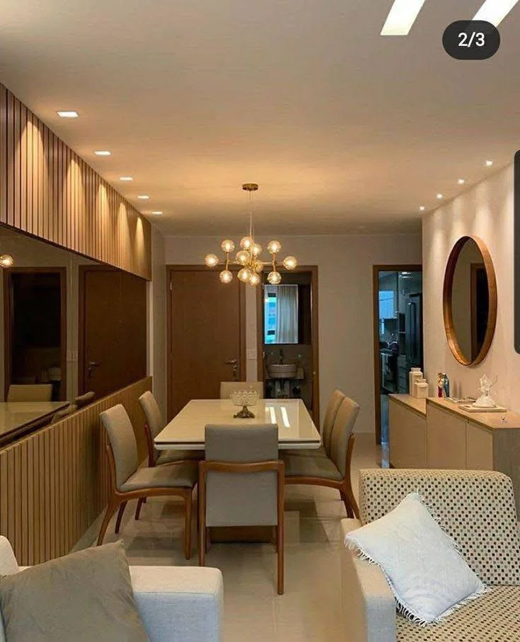 Dining room with a mirrored wall to enhance space, wood paneling, and layered lighting.