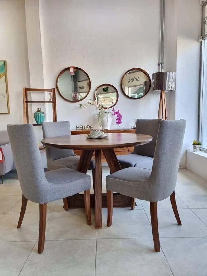 Dining room featuring a round wooden table, upholstered chairs, and a trio of round mirrors.