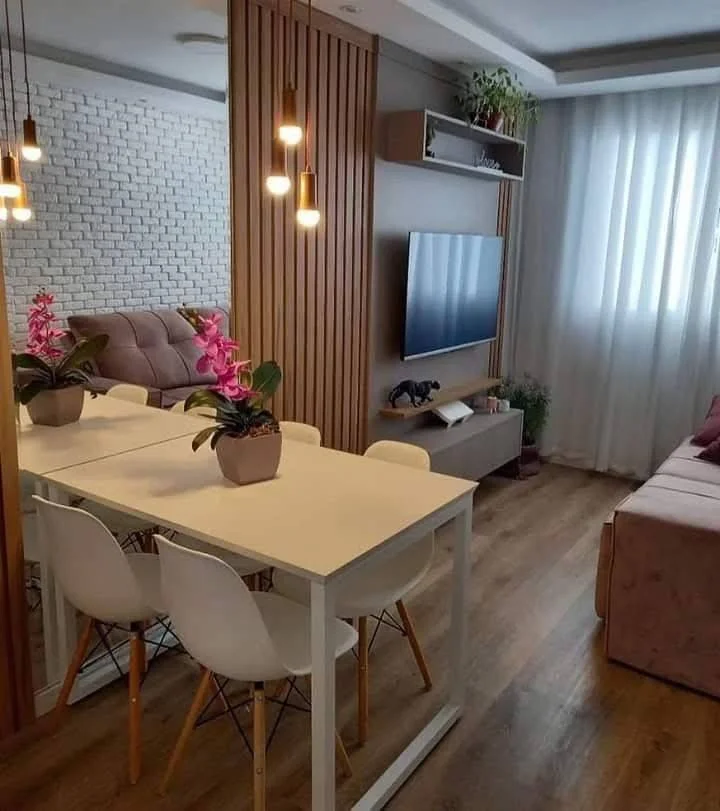 Dining area with a wood slat partition, a white table, and pendant lighting.