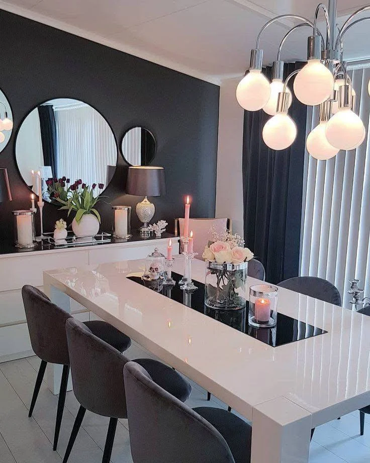 Elegant black and white dining room with velvet chairs and a statement chandelier.