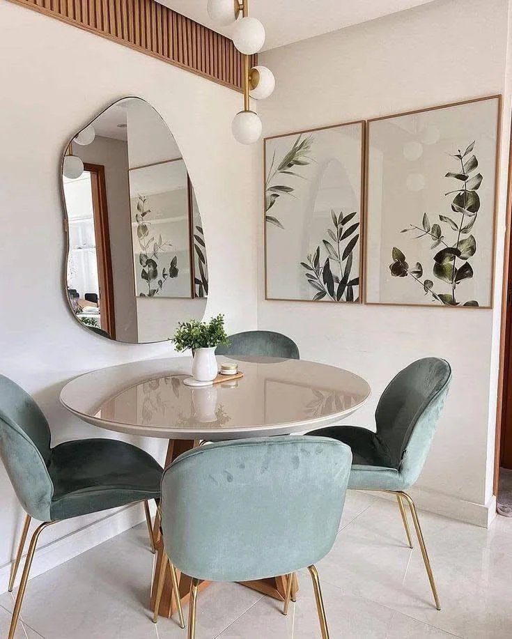 Pastel-toned dining room with a round table, velvet chairs, and botanical accents.