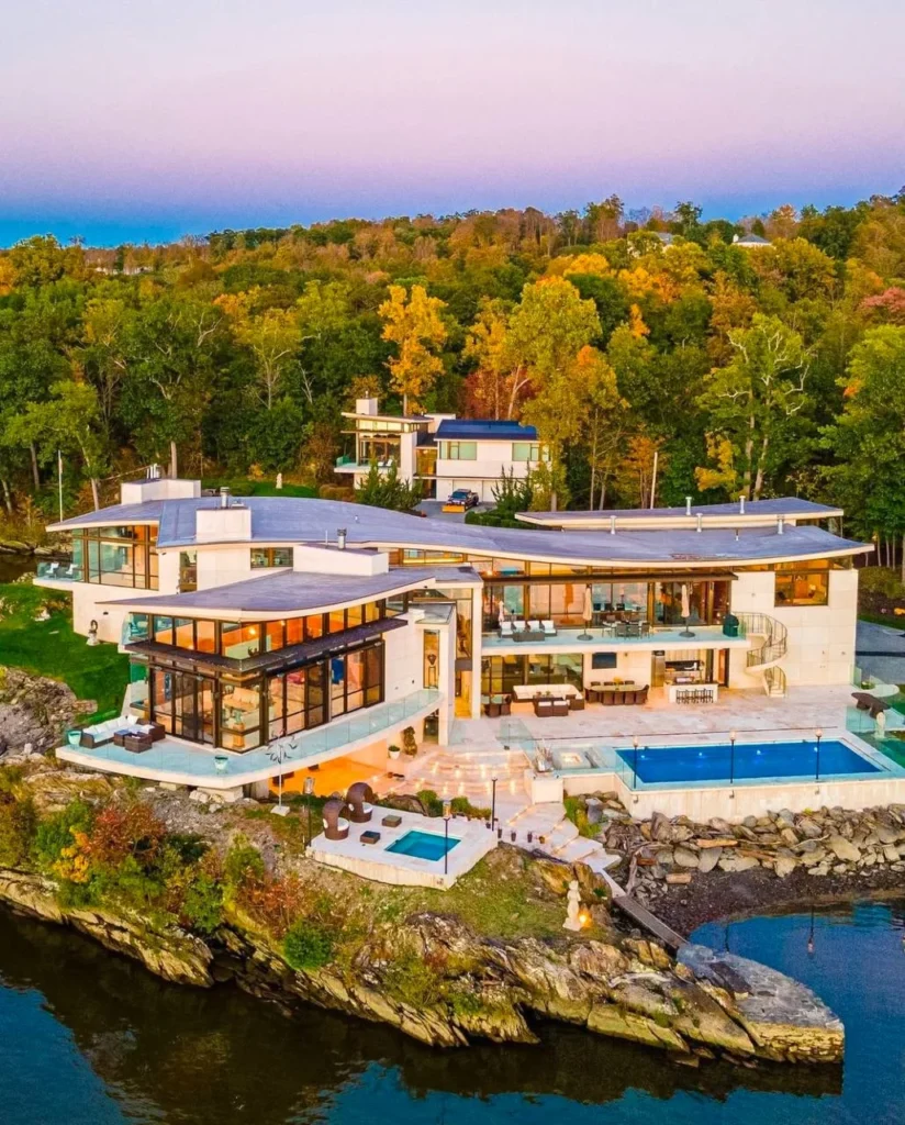 Luxury dream home exterior with cantilevered design and waterfront pool.