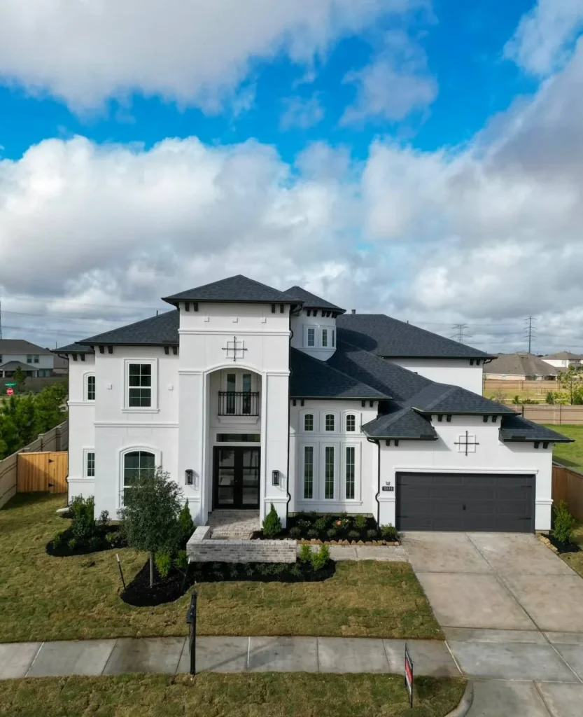 Luxury dream home exterior with white stucco and dark roof.