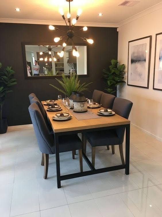 Modern dining room with black accent wall and industrial lighting.