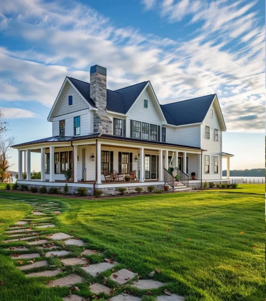 Modern farmhouse with stone chimney and large porch, lakeside view.