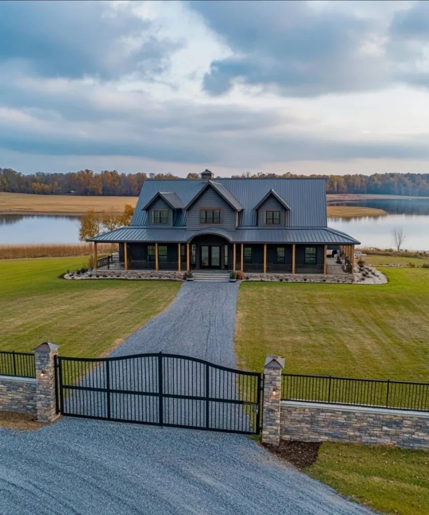 Modern farmhouse with dark exterior and gated entrance, lakefront property.