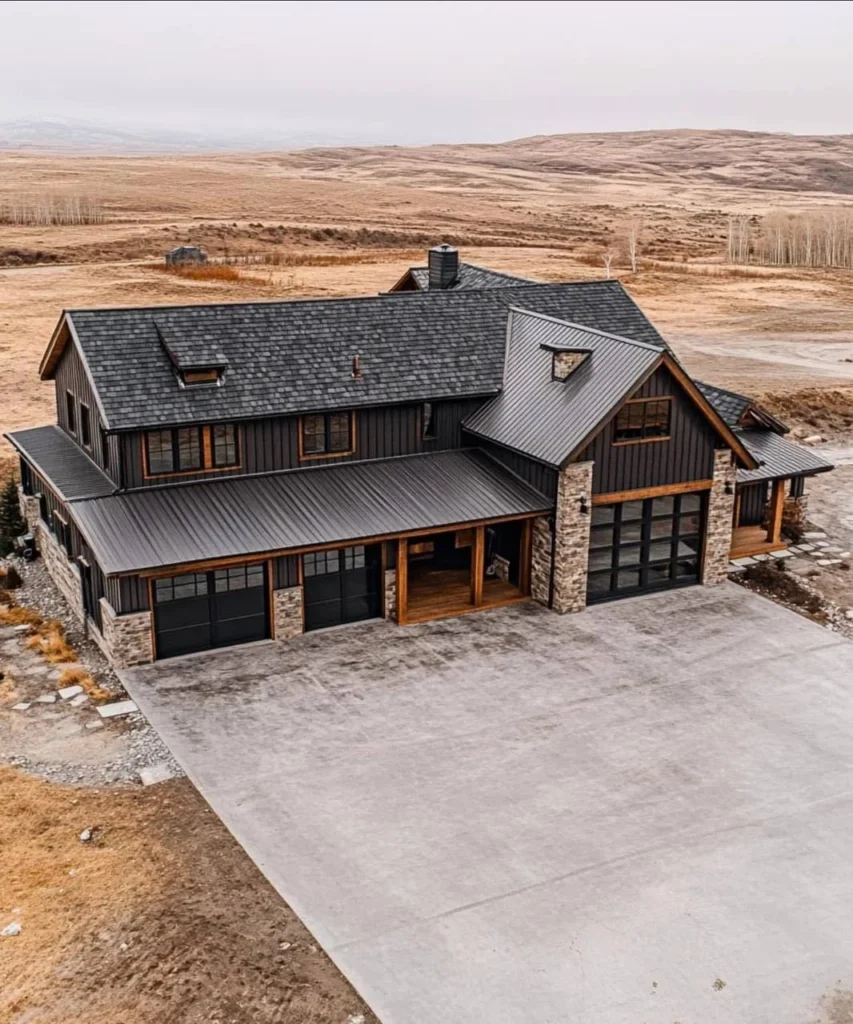 Modern industrial farmhouse with dark siding, metal roof, and glass garage doors.