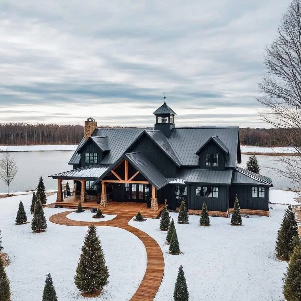 Dark modern farmhouse in a snowy landscape with a circular wooden pathway.