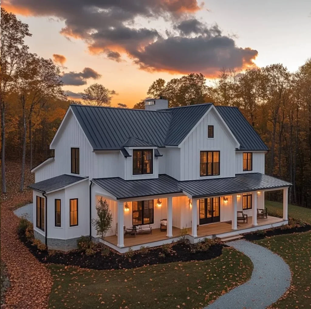 White modern farmhouse, barndominium style, with wrap-around porch at sunset.