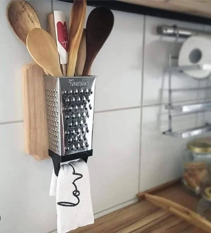 Recycled cheese grater used as a wall-mounted kitchen utensil holder.