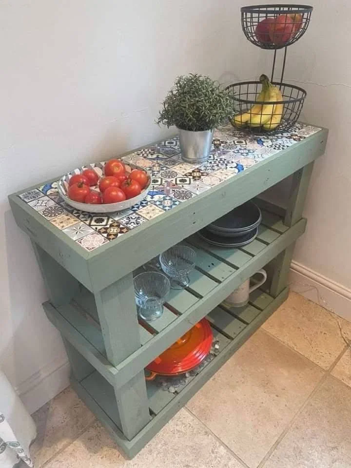 Recycled wooden pallets forming a shelving unit with a mosaic tile top.