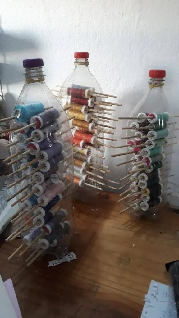 Recycled plastic bottles used as organizers for sewing thread spools.