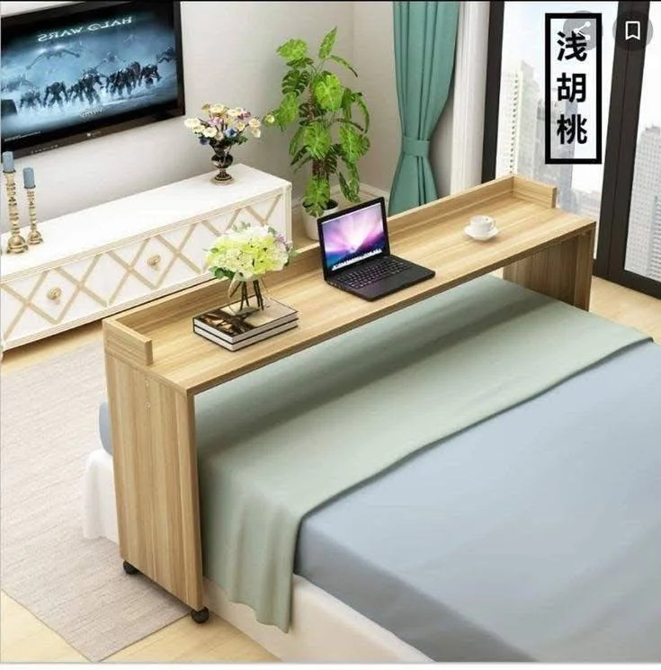 Wooden overbed table providing a workspace or surface over a bed in a bedroom.