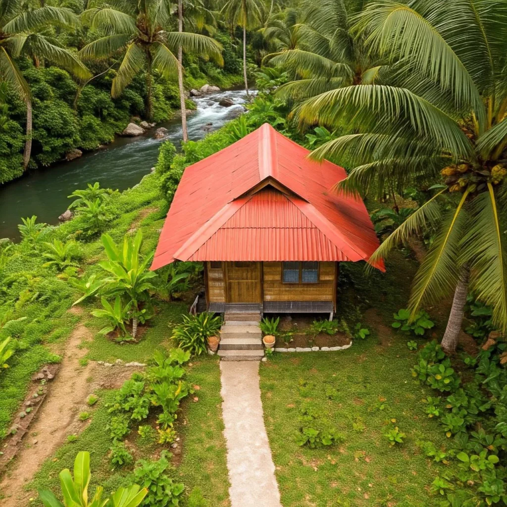 Tropical homestead with red roof nestled beside a river.