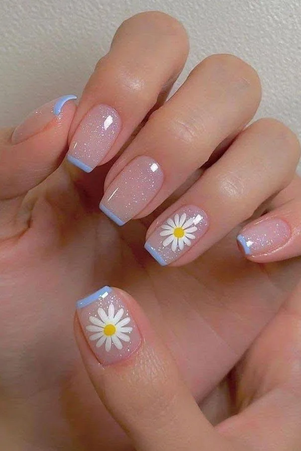 Short pink nails with daisy nail art and blue tips.