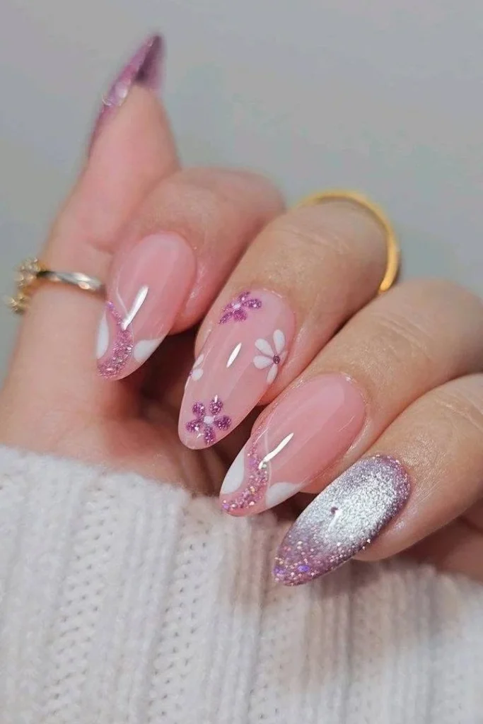 Short pink acrylic nails with glitter, rhinestones, white tips, and flower accents.