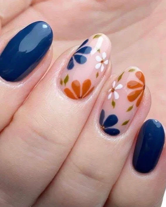 Short nails with blue and orange flower nail art on a sheer pink base.