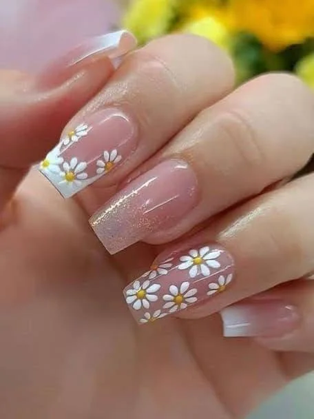 Short pink nails with rows of daisy nail art and a glitter accent nail.