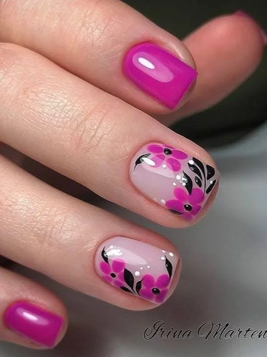 Short nails with fuchsia and black floral nail art on a sheer pink base.