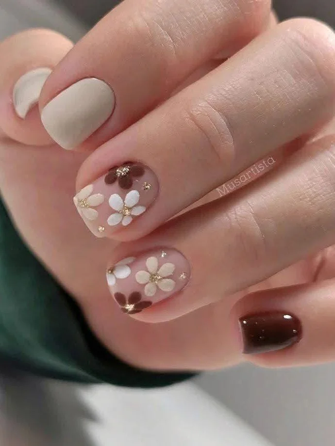 Short pink and brown nails with white flower and gold foil nail art.