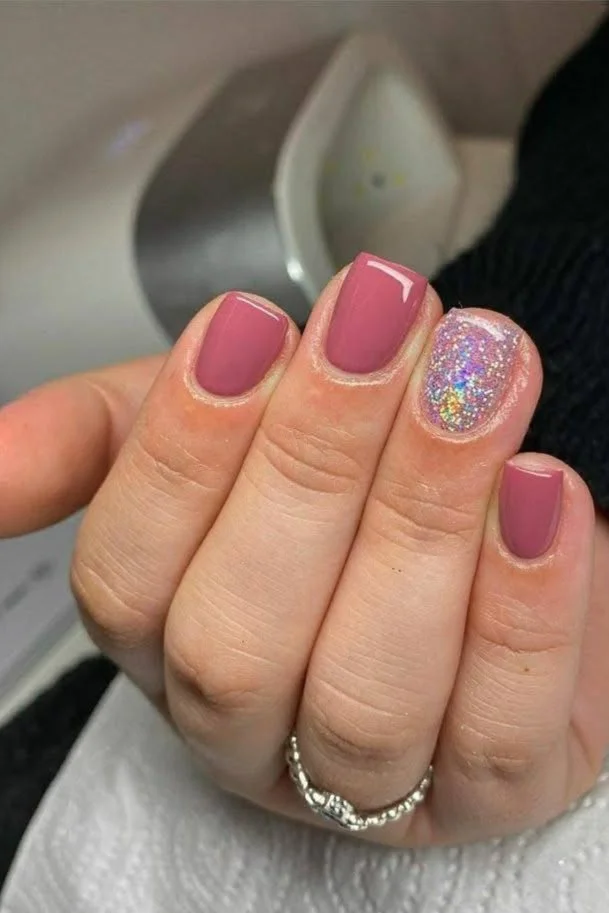 Short dusty rose nails with a single glitter accent nail.