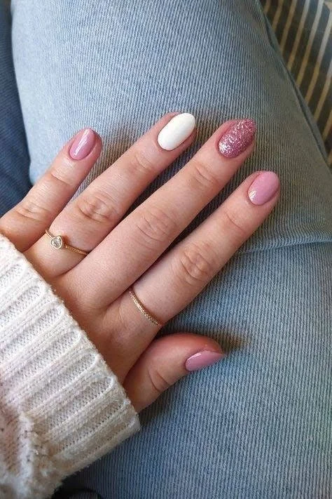 Short nails with pink, white, and pink glitter polish.