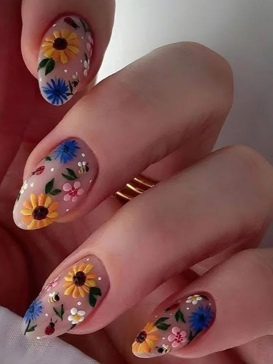 Short almond-shaped nails with colorful sunflower, ladybug, and floral nail art.