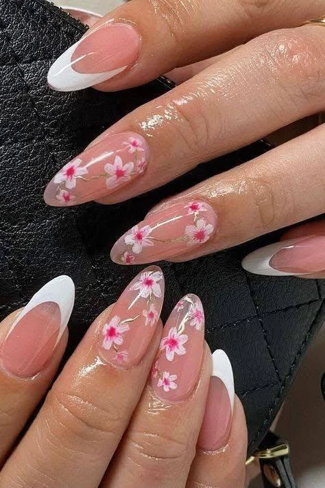 Short nails with white French tips and pink floral nail art on a sheer pink base.