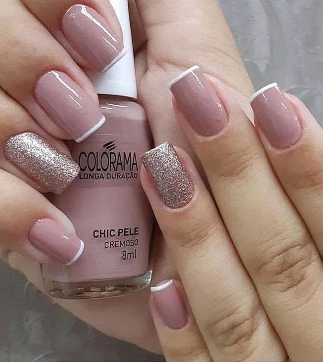 Short dusty rose nails with white French tips and silver glitter accent.