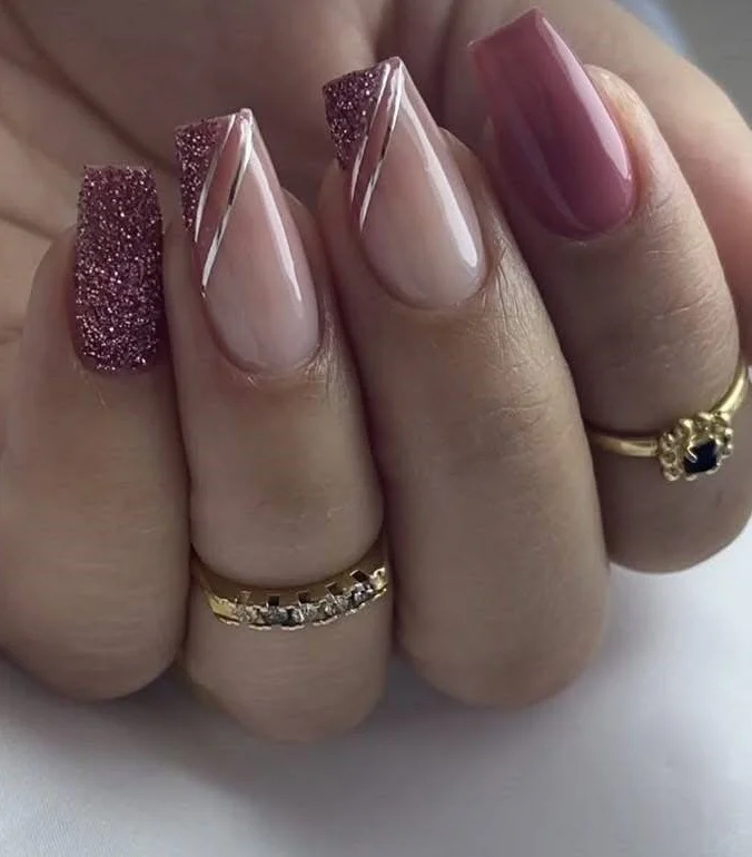 Short, peachy-pink nude nails with mauve and glitter V-shaped French tips.