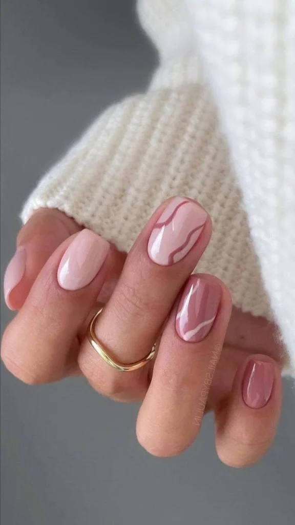 Short, pink nude nails with a pink and white marble accent nail.