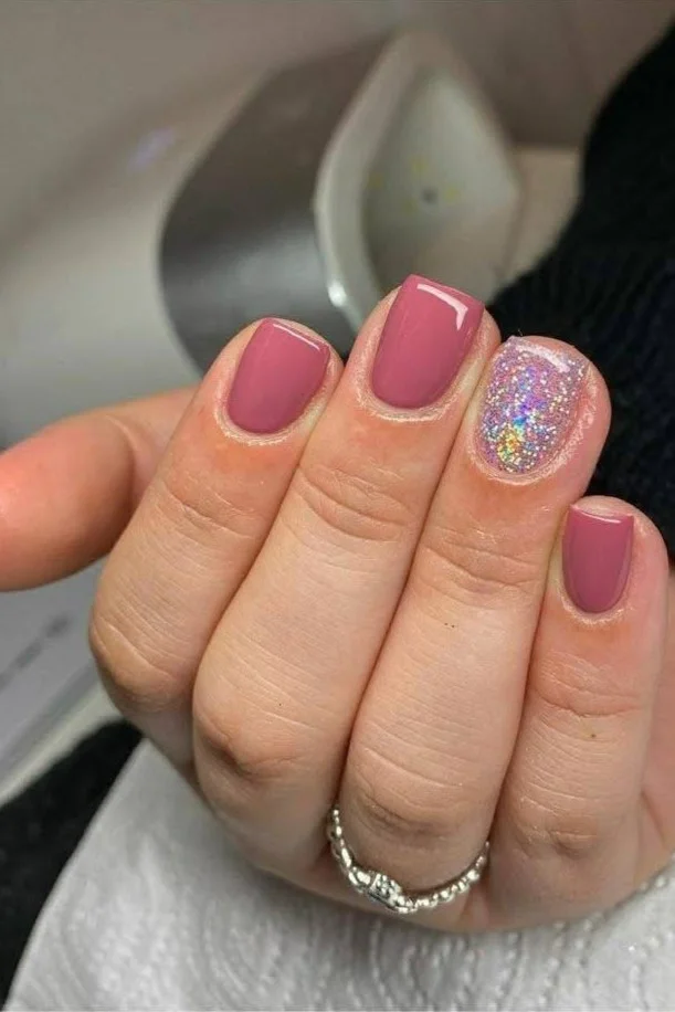 Short dusty rose nails with a holographic glitter accent nail.