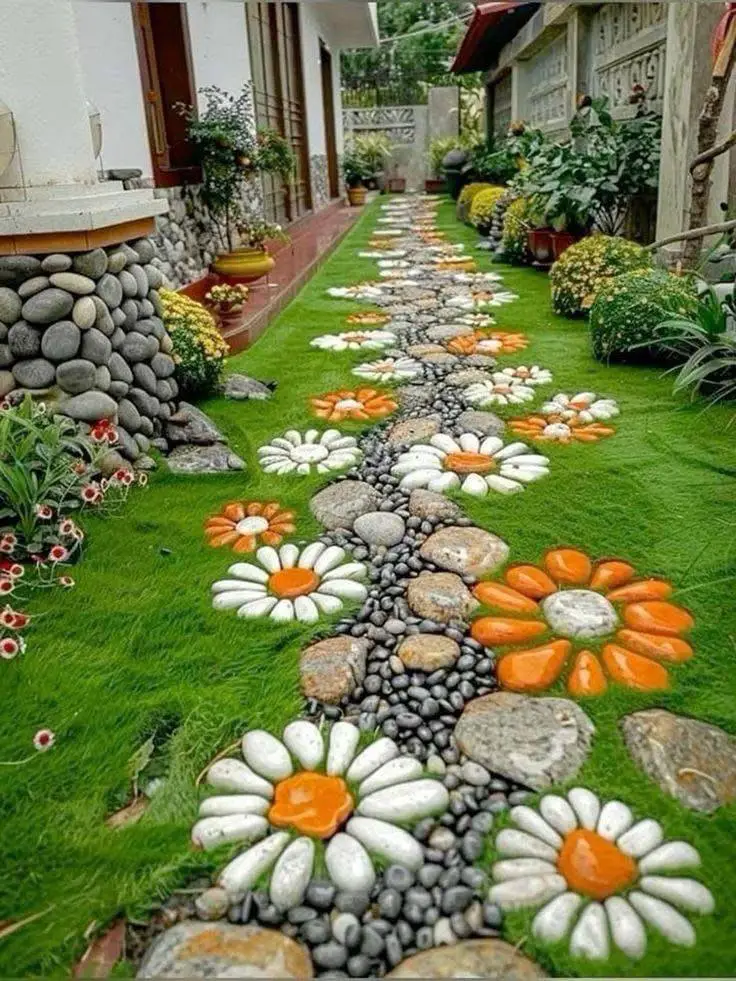 Garden path with flower designs made from various colored river stones, embedded in the grass.