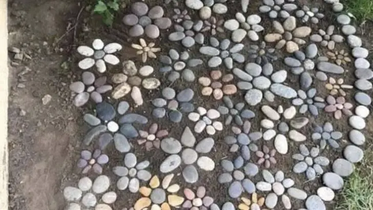 Garden bed filled with various flower shapes created from different colored and sized river stones.