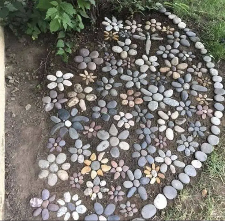 Garden bed filled with various flower shapes created from different colored and sized river stones.