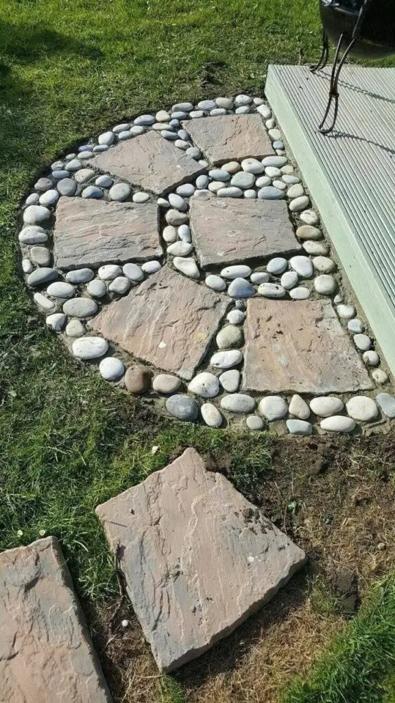 Garden path with large, square stepping stones, each bordered with small, light-colored river stones.