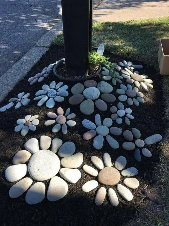 Garden bed with multiple flower shapes created from arranged river stones of different sizes and colors.