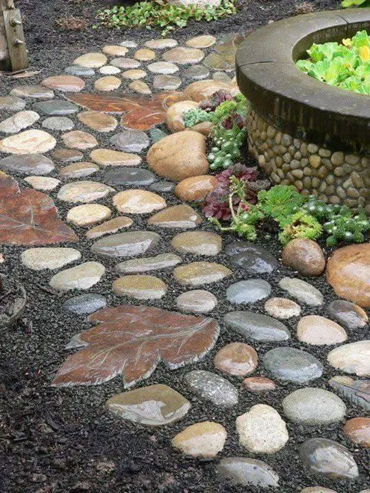 Garden border created with various sized and colored river stones and larger flat stones, alongside dark mulch.