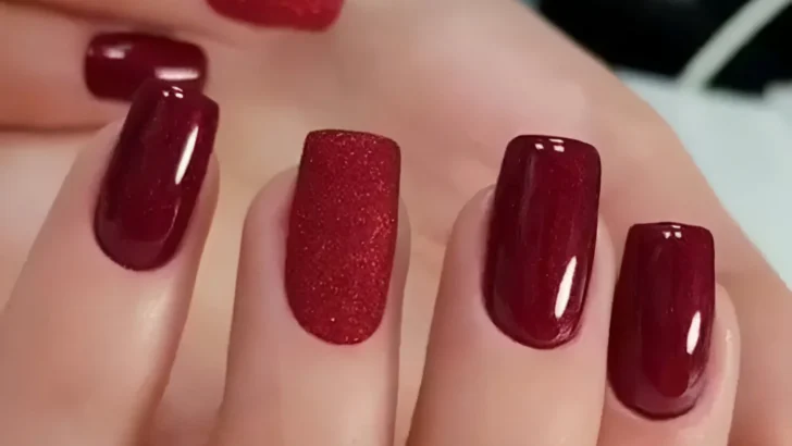 Dark red nails with textured glitter accent.