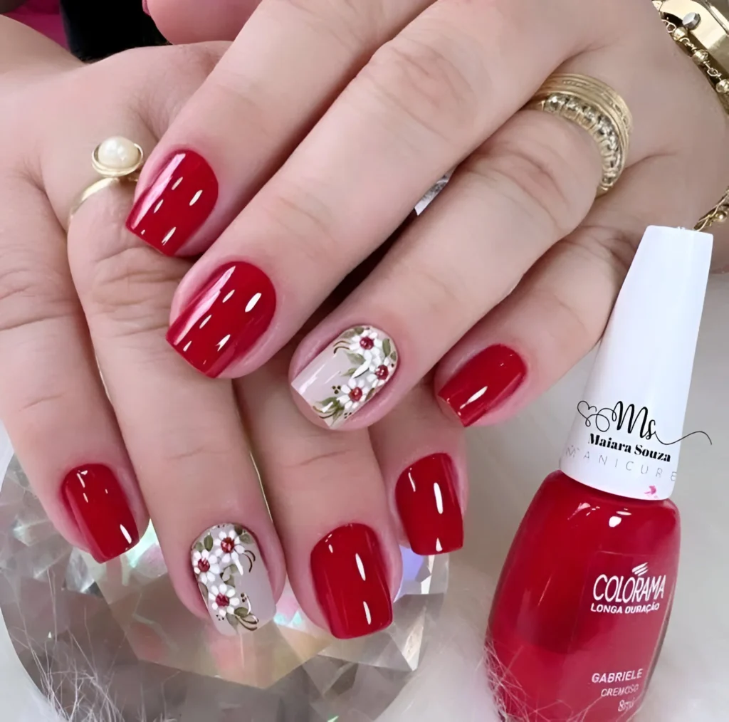 Red nails with floral accent nail art.