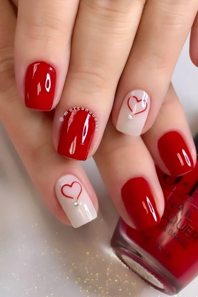 Minimalist red nails with small white heart accents, a sweet 2025 design.