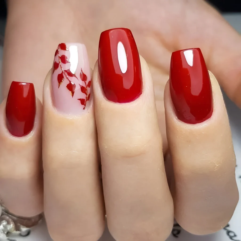 Glossy red nails with a pale pink and red vine accent nail for 2025.