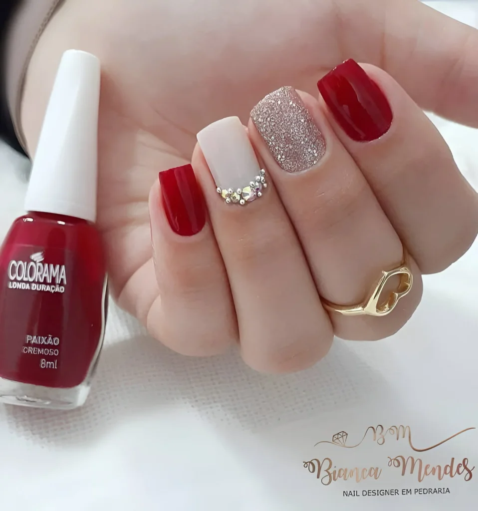 Red nails with crystal embellishments and glitter.