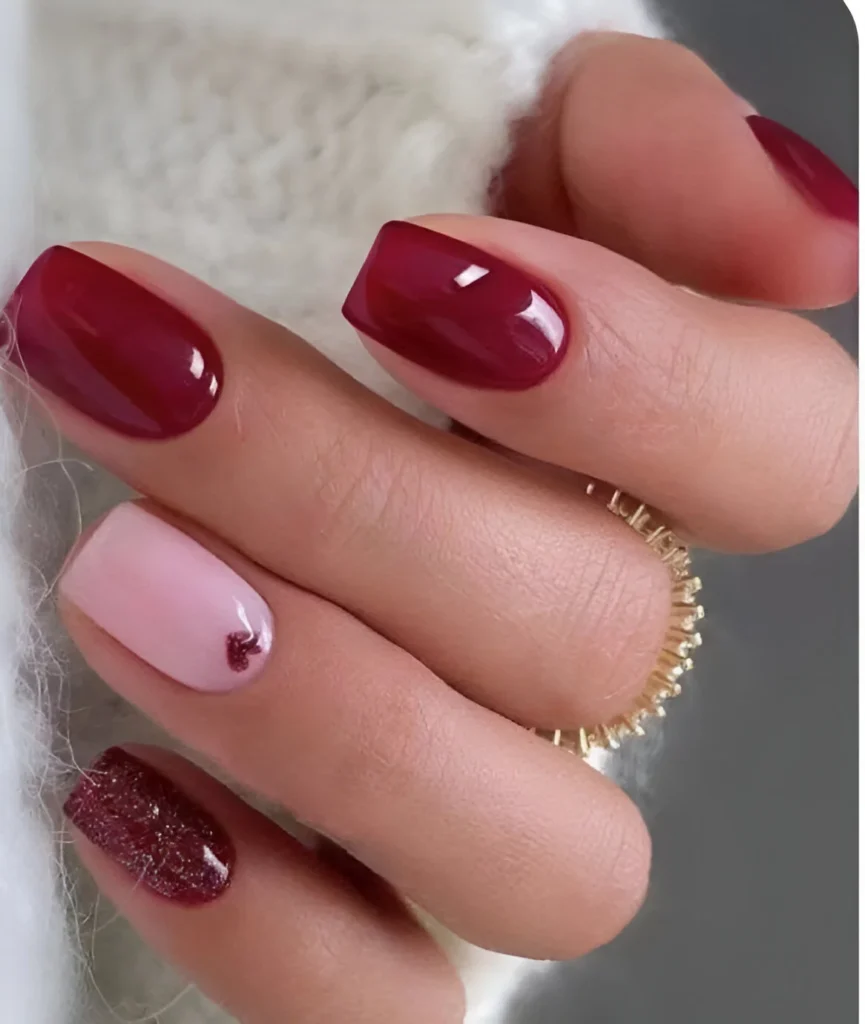 Red and pink nails with glitter and heart accents, perfect for Valentine's 2025.