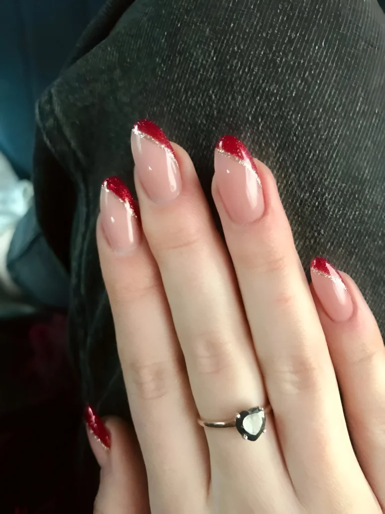 Nude nails with red glitter French tips – a glamorous 2025 nail design.