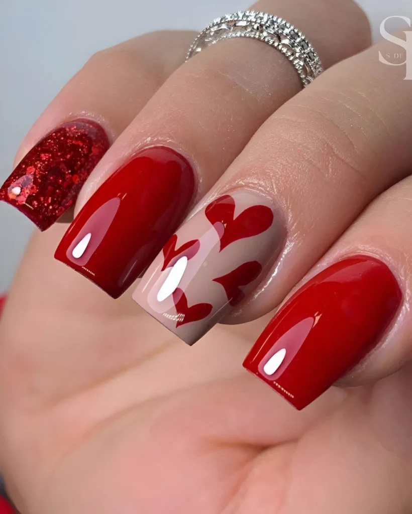 Red nails with glitter and overlapping heart accents, a glamorous finale for 2025. - Trending red nail designs