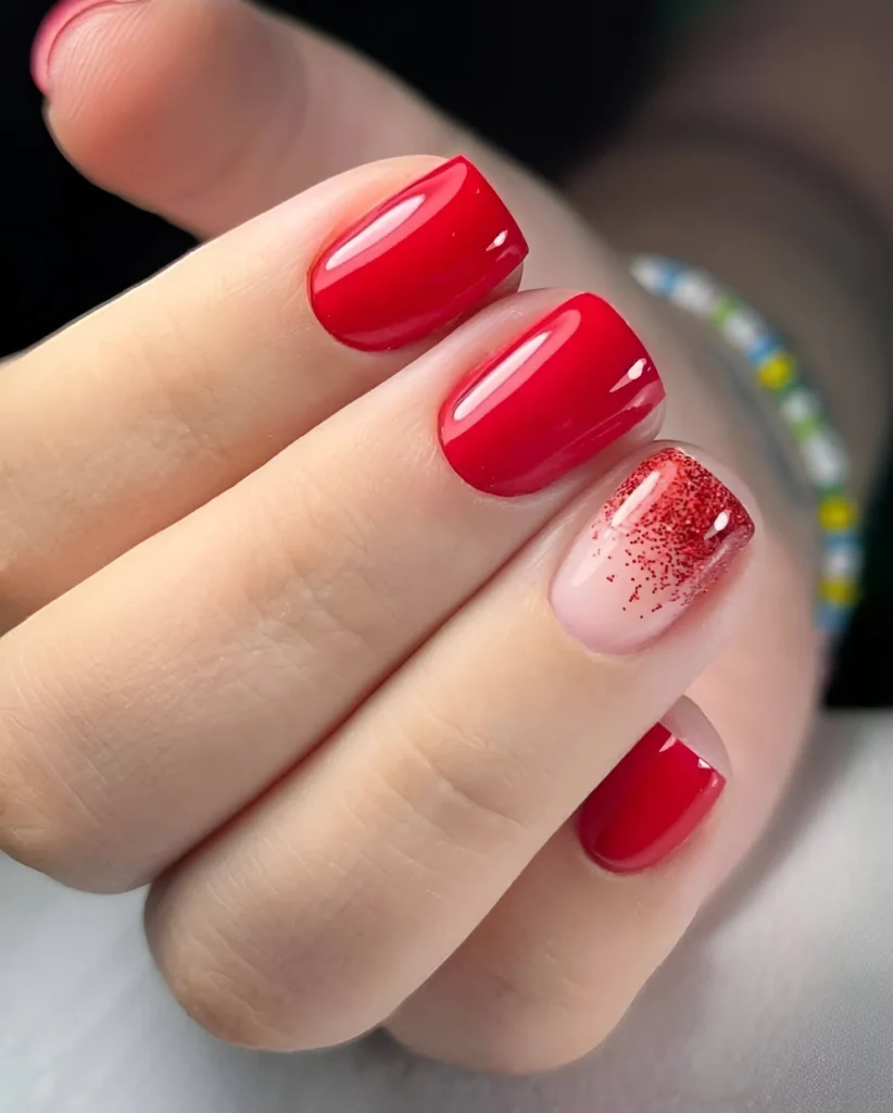 Trendy red nails with ombre glitter fade.