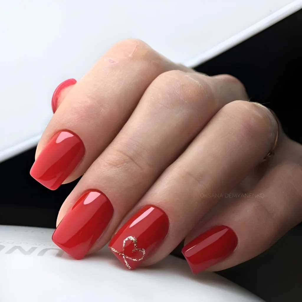 Classic red nails with a subtle gold heart outline accent – 2025 trend.