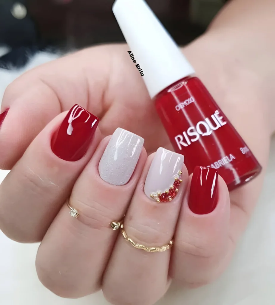 Red and white nails with textured design and gems.