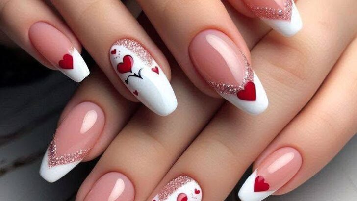 Coffin nails with peach-pink base, white French tips, red hearts, and glitter accents.